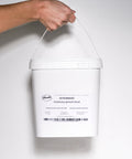 Ein weißer Eimer mit 2,5 kg gehackten, blonden Haselnüssen von Lemke, gehalten von einer Hand am Henkel. Perfekt für Backwaren, Desserts und die Herstellung hochwertiger Lebensmittel. Langlebige Verpackung mit klarer Produktkennzeichnung.